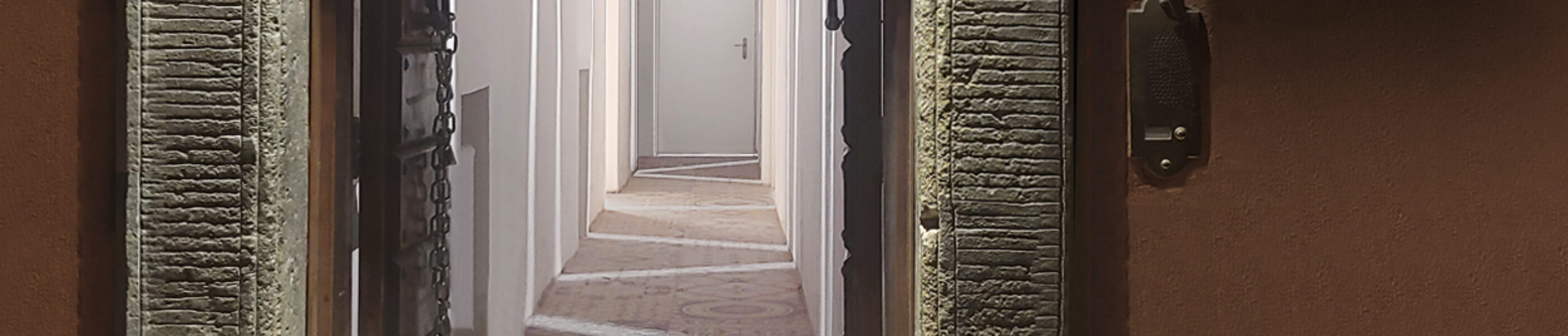 View of the illuminated entrance of Cisterna hotel in Trastevere