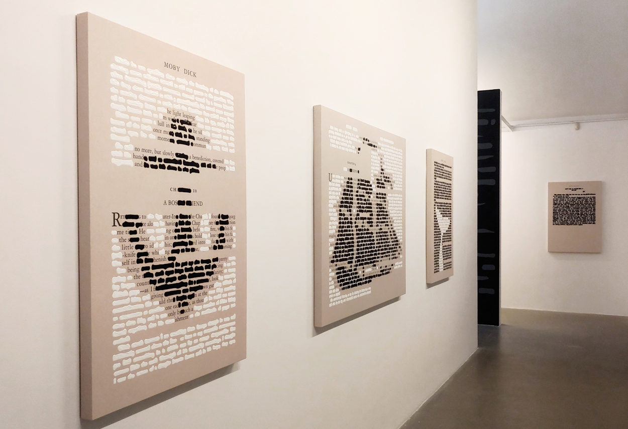 Le opere di Emilio Isgrò affisse al muro ed illuminate
